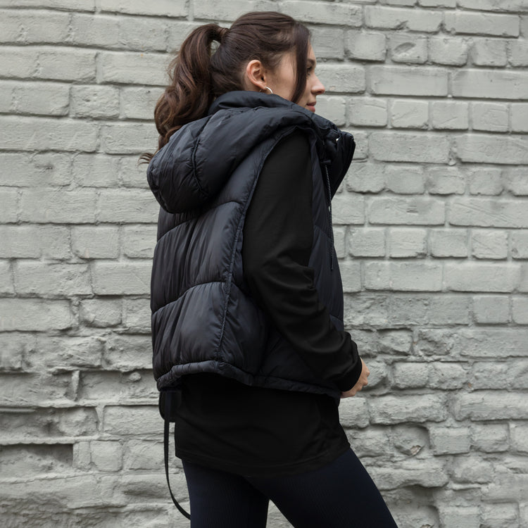 Model wearing a black TMiTH long sleeve tee under a black padded vest, back and side view; the back design is covered. The Man in The Hat 907 artist merch expressing complex PTSD handshake.