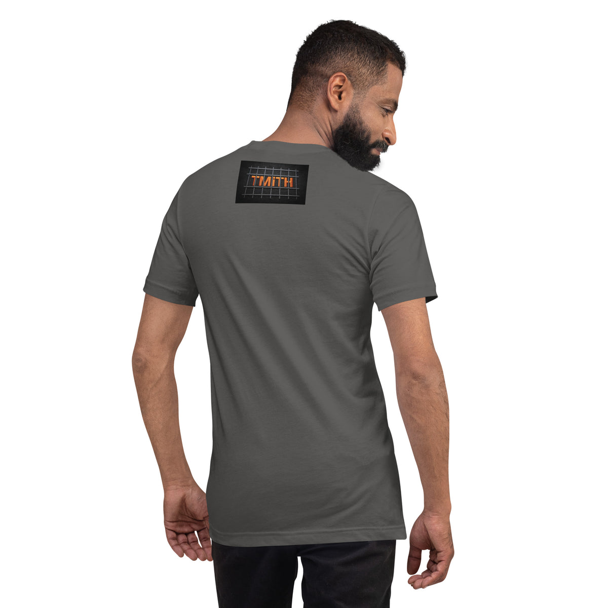 Model showing the back of a asphalt TMiTH T-shirt with orange lettering behind gray prison bars. The Man in The Hat 907 artist merch expressing PTSD and complex trauma expression.