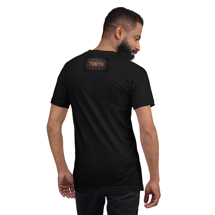 Model showing the back of a black TMiTH T-shirt with orange lettering behind gray prison bars. The Man in The Hat 907 artist merch expressing abuse-survivor solidarity.