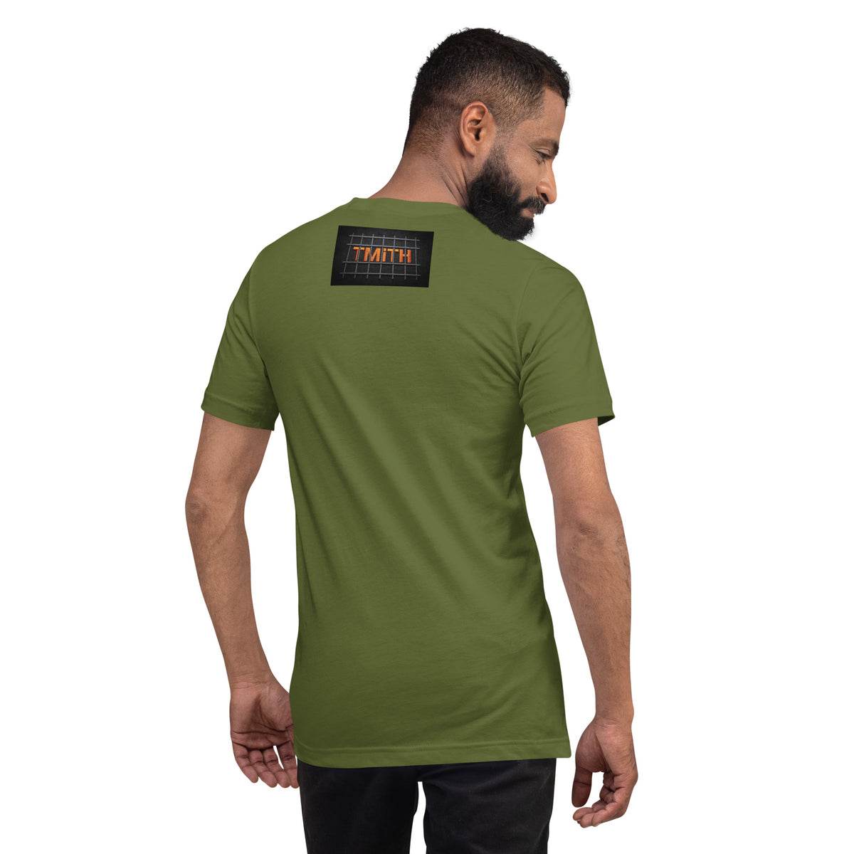 Model showing the back of a olive TMiTH T-shirt with orange lettering behind gray prison bars. The Man in The Hat 907 artist merch expressing generational trauma and breaking the silence.